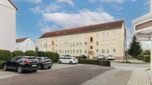 a large building with cars parked in a parking lot at Ferienwohnung mit Tageslichtbad in ländlicher Lage nahe Halle (Saale) in Landsberg
