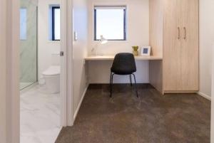 a bathroom with a desk and a chair in it at Beach Front Abode- 2 Bed 2 Bath in Christchurch