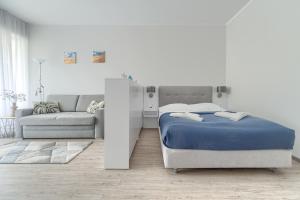 a white bedroom with a bed and a couch at Apartament Doris 3- Studio z wanną in Pobierowo