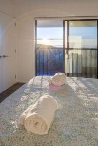 - deux serviettes assises sur un lit dans une chambre dans l'établissement Beach Front Abode- 2 Bed 2 Bath, à Christchurch