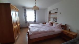 a bedroom with a bed with white sheets and a window at Bauernhof Madlhof in Neuschönau