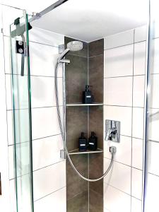 a shower with a hose in a bathroom at GastRoom Am Seefeld in Grafing