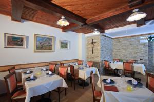 ファーイ・デッラ・パガネッラにあるHotel Stella Alpinaの白いテーブルと椅子、レンガの壁が特徴のレストラン