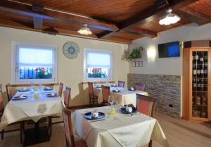 uma sala de jantar com mesas e toalhas de mesa brancas em Hotel Stella Alpina em Fai della Paganella