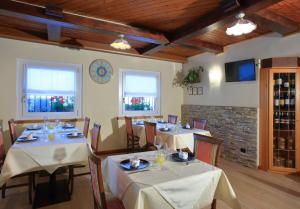 a dining room with tables with white tablecloths at Hotel Stella Alpina in Fai della Paganella