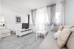 Górnośląska 17/19 by Homeprime في وارسو: غرفة معيشة بيضاء مع أريكة وتلفزيون