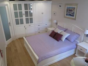 a bedroom with a bed with white cabinets and purple pillows at Studio Apartments Sonatina in Dubrovnik