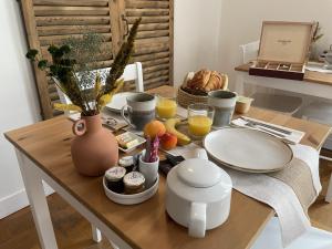 a table with food and drinks and a vase on it at Le Trouville - Hôtel de Charme in Trouville-sur-Mer