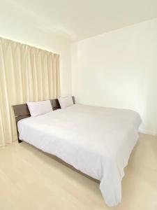 1 dormitorio blanco con 1 cama grande con sábanas blancas en SAPPHIRE -SEVEN Hotels and Resorts-, en Okinawa City