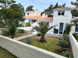 una casa blanca con palmeras en un patio en Maison, 150 m de la plage, la Tresson,Noirmoutier, en La Guérinière