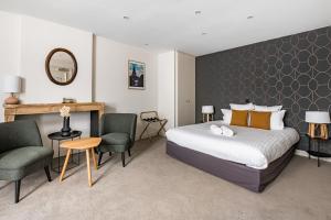 リヨンにあるル フェニックス オテルのベッド、椅子、鏡が備わる客室です。