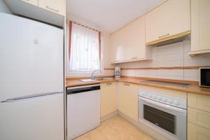 La cuisine est équipée de placards blancs et d'un réfrigérateur. dans l'établissement Estrella 2 2 1a spaniahome, à L'Alfas del Pi