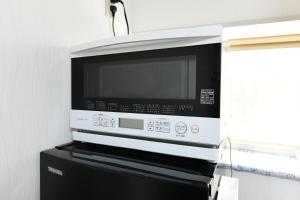 a microwave oven sitting on top of a black cabinet at JH Yellow Guest House in Tokyo