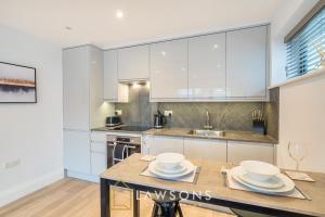 a kitchen with white cabinets and a table with dishes on it at Watt a Stay I Free EV Parking in Windsor