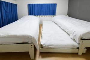 two twin beds in a room with blue curtains at JH Yellow Guest House in Tokyo