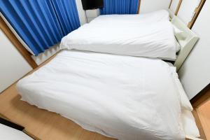 two beds in a room with white sheets at JH Yellow Guest House in Tokyo