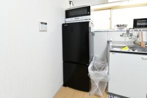 a black refrigerator with a microwave above it in a kitchen at JH Yellow Guest House in Tokyo