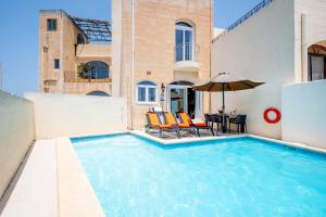 a swimming pool with a table and chairs and an umbrella at Veduta Holiday Home in Qala