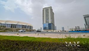 two cars driving on a road in front of buildings at Rare Holiday Homes - Close to Stadium - Canal View - Stadium Point - R811 - Dubai Sports City in Dubai