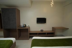 a room with two beds and a tv on the wall at Hotel Modi Samrat in Aurangabad