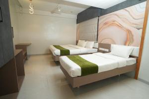 a room with two beds and a painting on the wall at Hotel Modi Samrat in Aurangabad