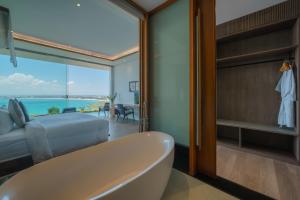 ein Badezimmer mit Badewanne und ein Schlafzimmer mit Aussicht in der Unterkunft Beyond The Sea - Luxe Sea View Villa in Jimbaran in Jimbaran
