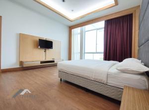 a bedroom with a bed and a flat screen tv at Bay Resort Penthouse by Evernent in Miri