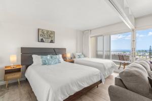 a bedroom with two beds and a couch and a window at Ilikai Hotel with Ocean View in Honolulu