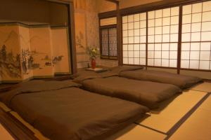 a row of beds sitting in a room with a wall of windows at Aioi Yanto 一日一組限定古民家宿 in Otaru