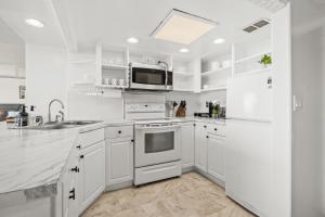 a white kitchen with white appliances and a microwave at Ilikai Hotel with Ocean View in Honolulu