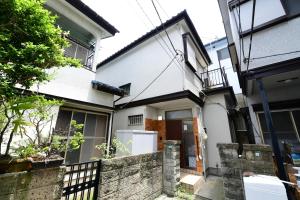 a white house with a fence in front of it at JH Yellow Guest House in Tokyo