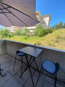 d'une table et de deux chaises sur un balcon avec un parasol dans l'établissement Appartement cosy climatisé dans résidence fermée, à Sarrola-Carcopino