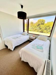 two beds in a room with a large window at Casa amoblada Chicureo Santiago in Colina