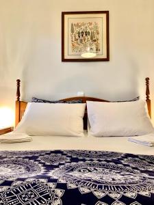 1 cama con 2 almohadas y una foto en la pared en Aggelos and Thisbe Chania Suburbs Sea View Guest House, en La Canea
