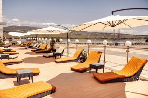 una fila de sillas y sombrillas en una cubierta en Hotels & Preference Hualing Tbilisi, en Tiflis