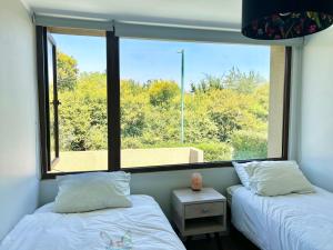two beds in a room with a large window at Casa amoblada Chicureo Santiago in Colina