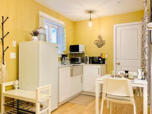 a kitchen with a white refrigerator and a table and chairs at Private Guest Suite in Little Italy - King Bed - Free Parking - Central Location in Vancouver