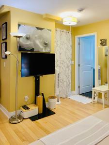 sala de estar con paredes amarillas y TV de pantalla plana. en Private Guest Suite in Little Italy - King Bed - Free Parking - Central Location, en Vancouver