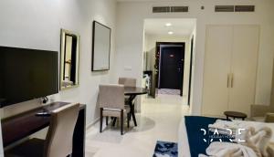 a living room with a tv and a table and chairs at Spacious Studio APT - Near Expo 2020 - Dubai South R410 in Dubai