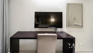 a desk with a television and a chair in a room at Rare Holiday Homes offers Luxurious apartment with desert View - Near Expo City - R451 in Dubai