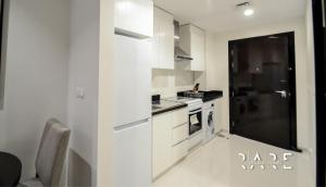 a kitchen with white cabinets and a stove top oven at RARE Holiday Homes - Pool View - Near Expo City - Modern Studio - R724 in Dubai