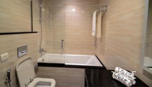a bathroom with a tub and a toilet and a sink at Pool View - Near Expo 2020 - Ultra Modern Studio in Dubai