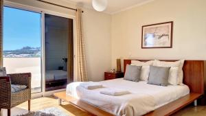 Un dormitorio con una cama y una ventana grande. en Lucy Sweet Home by LovelyStay, en Caniço