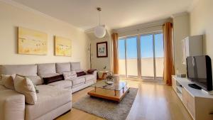 Una sala de estar con un sofá y un televisor. en Lucy Sweet Home by LovelyStay, en Caniço