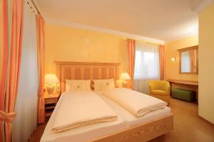 a bedroom with a large bed and a chair at Ringhotel Sonneck in Bad Wörishofen