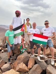 a group of people standing on rocks holding a flag at Adam Bedouin camp in Wadi Rum