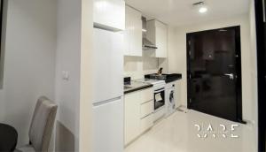 a kitchen with white cabinets and a stove top oven at Rare Holiday Homes - Modern apartment - Near EXPO City - Desert view in Dubai