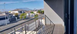 Elle comprend un balcon offrant une vue sur une rue de la ville. dans l'établissement LND GUEST HOUSE, à Bloubergstrand