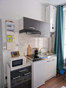 a small kitchen with a microwave and a sink at Gîte de la Basilique Â 10 Minutes du Château in Blois