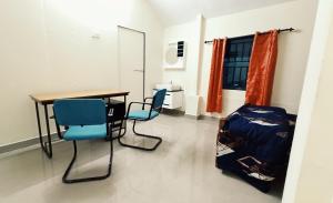 Cette chambre dispose d'une table, de deux chaises et d'un bureau. dans l'établissement chaithanya wellness centre, à Vagamon
